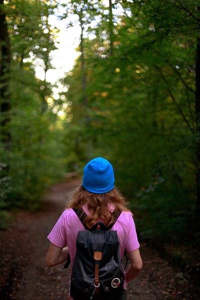 During the day, a pink long sleeve shirt, wearing a blue knitted hat woman standing in the forest
